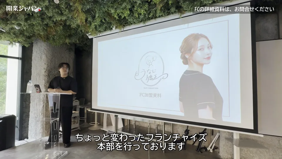 うなじ矯正のFC加盟資料の表紙スライドの前でピッチを始める永野海吏代表