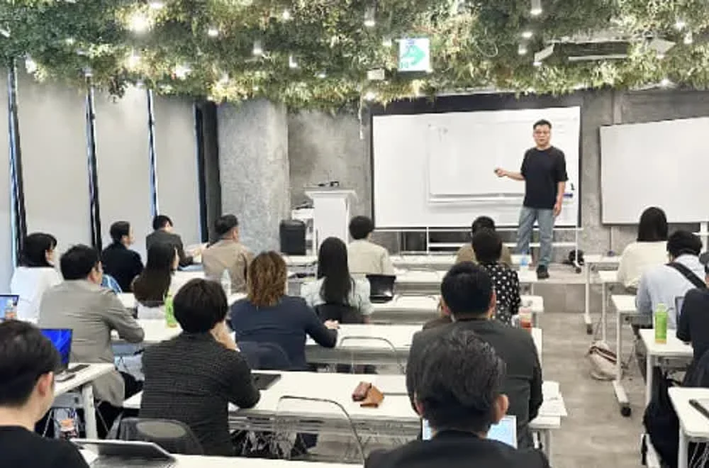 フランチャイズツアーの勉強会。参加者が着席し、講師がホワイトボードの前で解説している様子